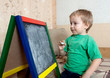 child draws on  blackboard with chalk