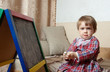 child draws on  blackboard with chalk