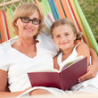 Rest in the garden - mother and daughter reading in hammock
