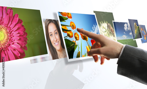 Photo: touchscreen interface: man hand reaching images on the screen touchscreen interface: man hand reaching images on the screen