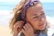 Young curly hair woman putting on earring