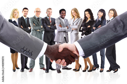 Photo: shaking hands and business team formed of young businesspeople shaking hands and business team formed of young businesspeople