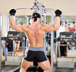 Bodybuilder shakes his back on the simulator. Back view