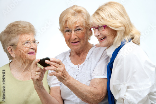 Photo: Elderly female friends with mobile device. Elderly female friends with mobile device.