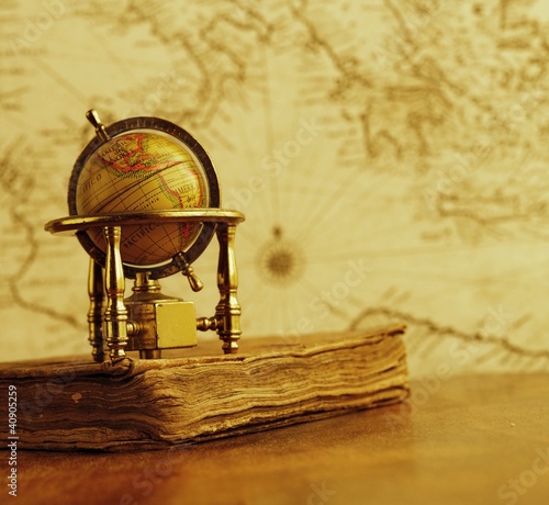 Foto: Globe and vintage book against map on a wall. Globe and vintage book against map on a wall.
