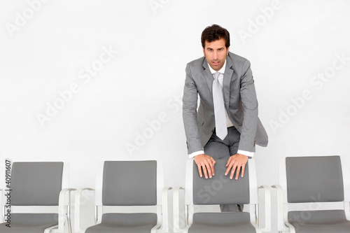 Photo: Man standing by chairs in waiting room Man standing by chairs in waiting room