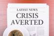 The newspaper CRISIS AVERTED  and coffee