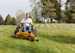 Senior man on zero turn lawn mower on turf