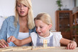 Young woman and her daughter playing dominoes