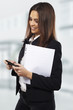 Business woman sending text message on mobile phone at office