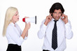 woman talking through a megaphone and a man plugging his ears