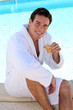 Man with juice on the edge of pool