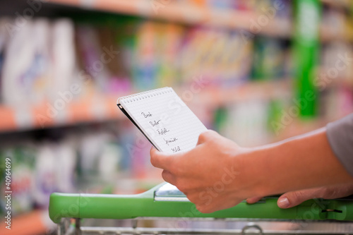 Photo: Junge Frau schiebt Einkaufswagen in Supermarkt Junge Frau schiebt Einkaufswagen in Supermarkt