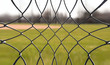 Looking at a baseball field through metal fencing - an abstract