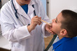 Photo: Doctor checking throat of a little boy with tongue depressor Doctor checking throat of a little boy with tongue depressor