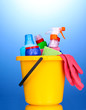 Bucket with cleaning items on blue background