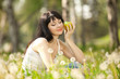 Cute woman eating the apple in the park with dandelions