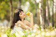 Cute woman eating the apple in the park with dandelions