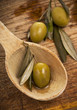 olive in spoon on a wooden table olive in spoon on a wooden table