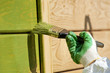Foto: hand with a paint brush painting wooden wall in green hand with a paint brush painting wooden wall in green
