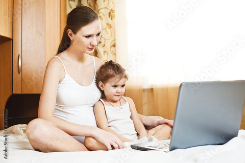 Photo: happy pregnant mother and child with laptop computer happy pregnant mother and child with laptop computer