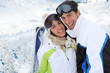 Couple standing on a snowy mountain in ski outfit