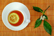 vibrant tea with lemon slice and blossom on bamboo mat. top view