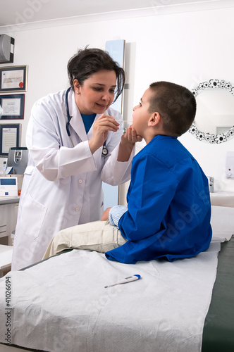 Photo: Pediatrician examining child’s throat with tongue depressor Pediatrician examining child’s throat with tongue depressor