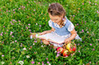 little girl sitting on grass with apples and book