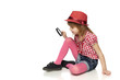 Full length of little girl sitting on floor with magnifier