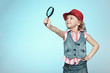 Little girl with magnifying glass, isolated on blue