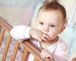 Funny small baby sucking fingers standing in bed and looking. Cl Funny small baby sucking fingers standing in bed and looking. Cl