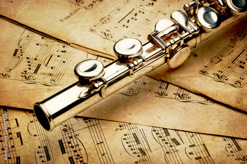 Photo: Silver flute on an ancient musical background Silver flute on an ancient musical background