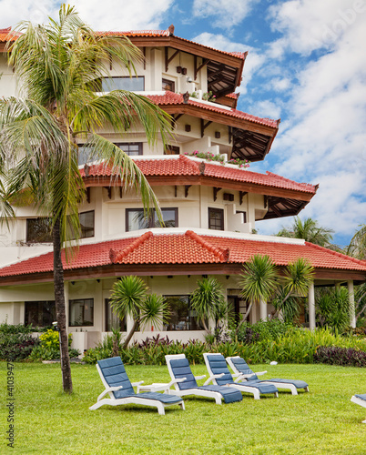 Photo: Some free chaise lounges on a lawn before hotel in tropics Some free chaise lounges on a lawn before hotel in tropics