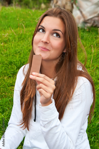 Photo: Chica comiendo chocolate mirando arriba Chica comiendo chocolate mirando arriba