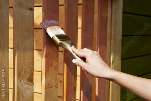 Foto: woman's hand with a paint brush painting wooden terrace in pink woman's hand with a paint brush painting wooden terrace in pink