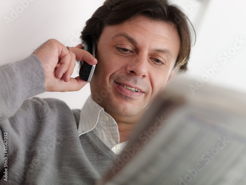 Photo: adult man reading stock exchange listings at home adult man reading stock exchange listings at home