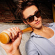 Portrait of young guy with bat leaning on the wall Portrait of young guy with bat leaning on the wall