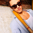 Portrait of young guy with bat leaning on the wall