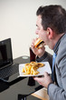 Businessman eating junk food while working
