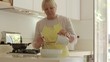Retired woman speaking on telephone and preparing food at home