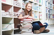 Smiling young adult woman reading  book in library