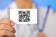 Doctor holding business card with health care QR code on blue