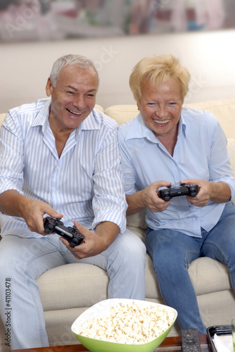 Photo: Pareja de señores jugando vídeo juego en casa. Pareja de señores jugando vídeo juego en casa.