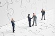Foto: Business figures shaking hands on a puzzle Business figures shaking hands on a puzzle