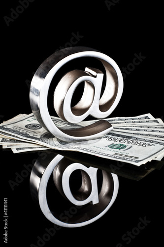 Photo: At symbol paperweight on a pile of 100 dollar bills At symbol paperweight on a pile of 100 dollar bills