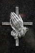 Betende Hände vor Kreuz auf dunklem Hintergrund