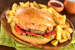 Hamburger mit Pommes auf rustikalem Holzteller
