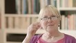 Happy senior woman with glasses reading book at home
