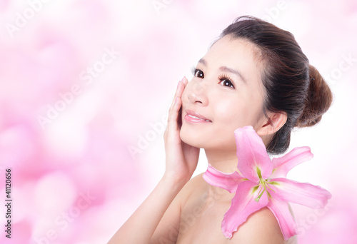 Photo: skincare woman hand touch face with pink flower skincare woman hand touch face with pink flower